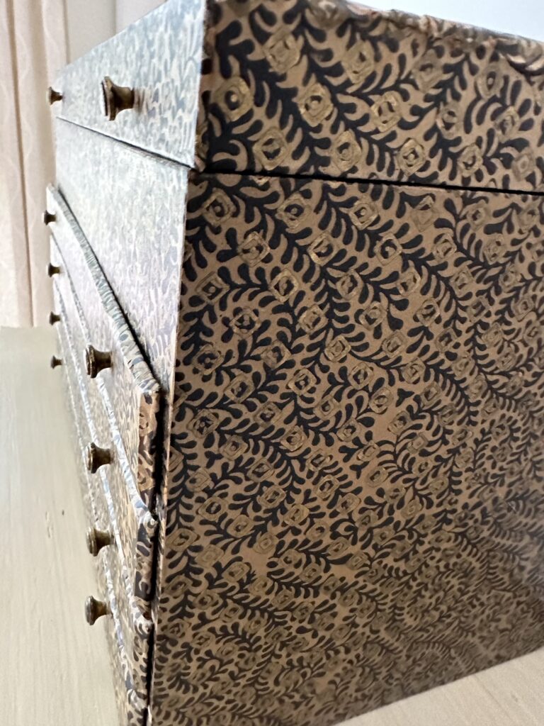 Repurposing a jewelry box using an intricate, muted gold and blue wood-block print patterned book-binding paper 