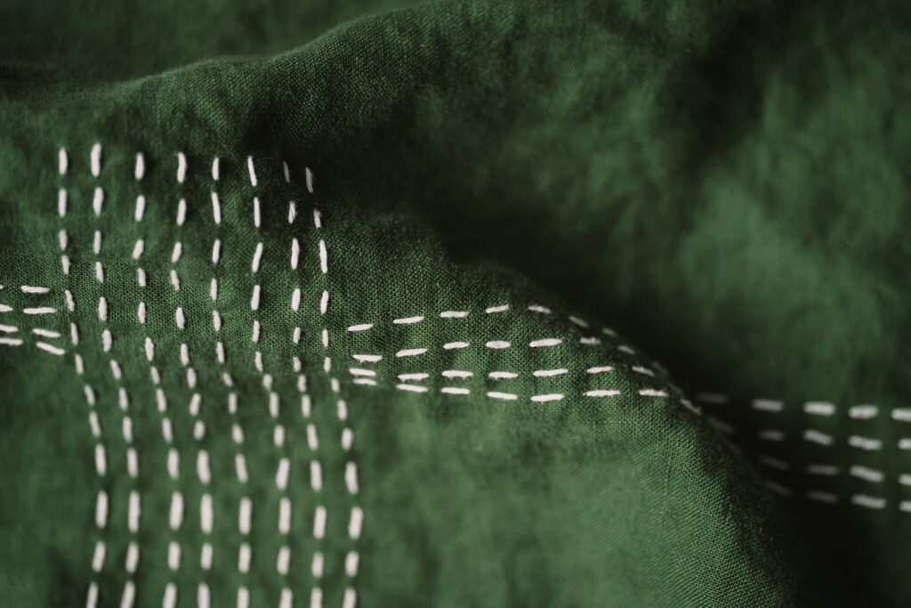 White thread stitching in sashiko style on repurposed forest green linen